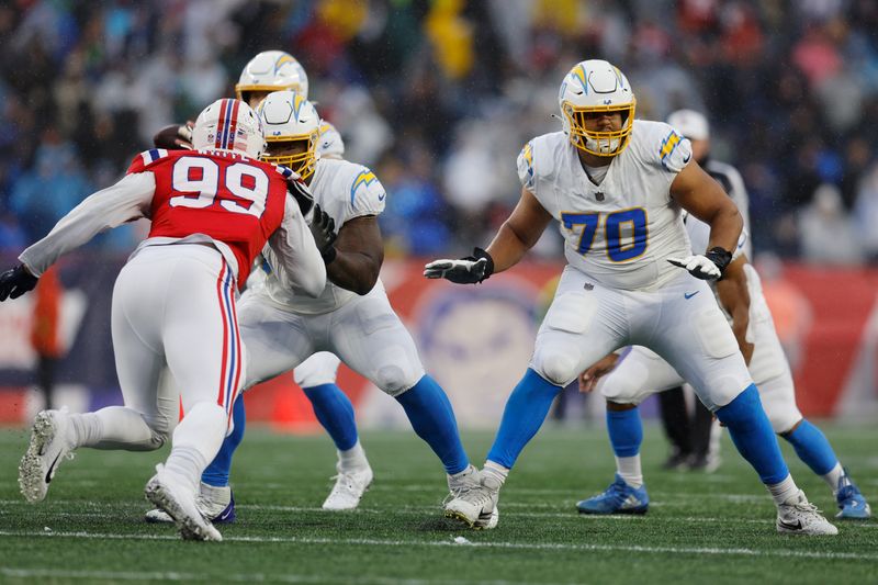 Los Angeles Chargers offensive tackle Rashawn Slater (70) and New England Patriots defensive end Keion White (99) during the first half of an NFL football game, Sunday, Dec. 3, 2023, in Foxborough, Mass. (AP Photo/Michael Dwyer)