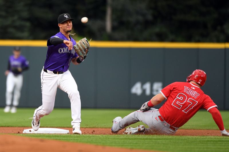 Sep 20, 2025; Denver, Colorado, USA; Colorado Rockies shortstop Ezequiel Tovar (14) turns a double play ahead of the slide by Los Angeles Angels designated hitter Mike Trout (27) during the first inning at Coors Field. Mandatory Credit: Christopher Hanewinckel-Imagn Images