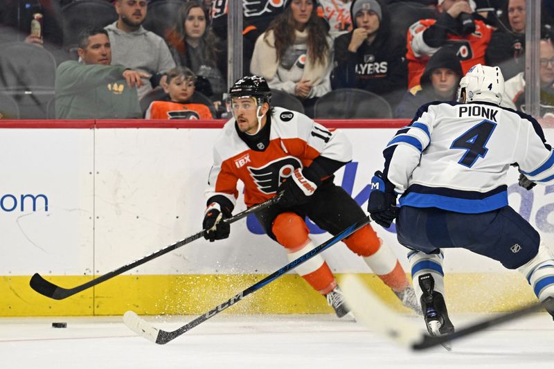 Oct 16, 2025; Philadelphia, Pennsylvania, USA; Philadelphia Flyers right wing Travis Konecny (11) controls the puck against Winnipeg Jets defenseman Neal Pionk (4) during the second period at Wells Fargo Center. Mandatory Credit: Eric Hartline-Imagn Images