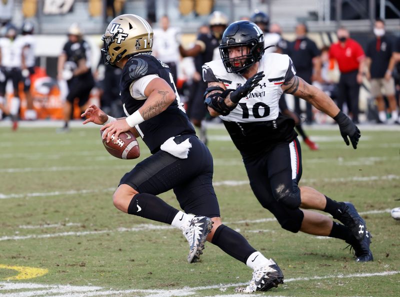 Nov 21, 2020; Orlando, Florida, USA; UCF Knights quarterback Dillon Gabriel (11) runs away from Cincinnati Bearcats linebacker Brody Ingle (10) during the first quarter at the Bounce House. Mandatory Credit: Reinhold Matay-USA TODAY Sports