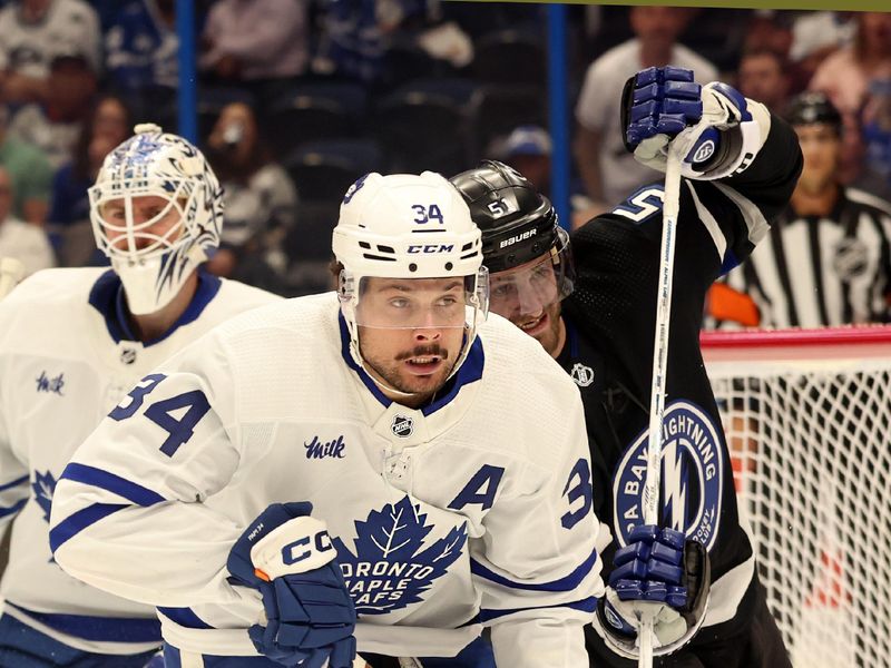 Apr 17, 2024; Tampa, Florida, USA; Toronto Maple Leafs center Auston Matthews (34) and Tampa Bay Lightning left wing Austin Watson (51) skate after the puck during the third period at Amalie Arena. Mandatory Credit: Kim Klement Neitzel-USA TODAY Sports