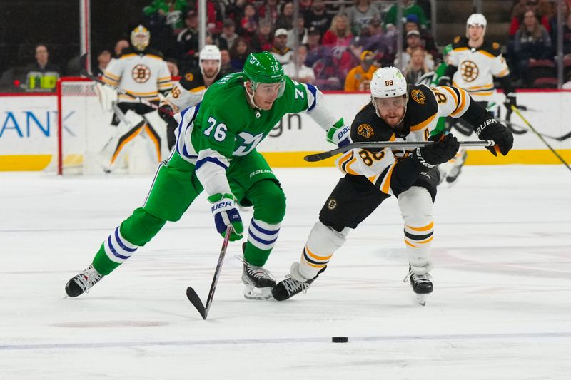 Mar 26, 2023; Raleigh, North Carolina, USA;  Boston Bruins right wing David Pastrnak (88) and Carolina Hurricanes defenseman Brady Skjei (76) chase after the loose puck during the second period at PNC Arena. Mandatory Credit: James Guillory-USA TODAY Sports