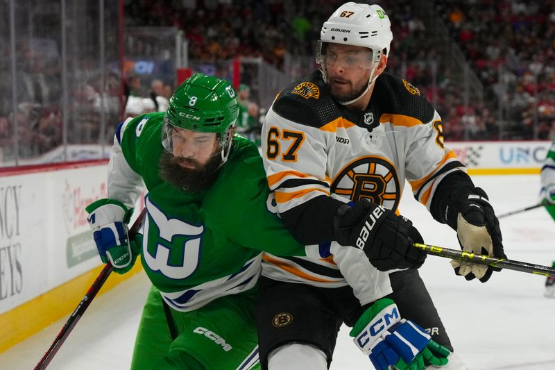 Mar 26, 2023; Raleigh, North Carolina, USA;  Boston Bruins defenseman Jakub Zboril (67) and Carolina Hurricanes defenseman Brent Burns (8) battle during the first period at PNC Arena. Mandatory Credit: James Guillory-USA TODAY Sports