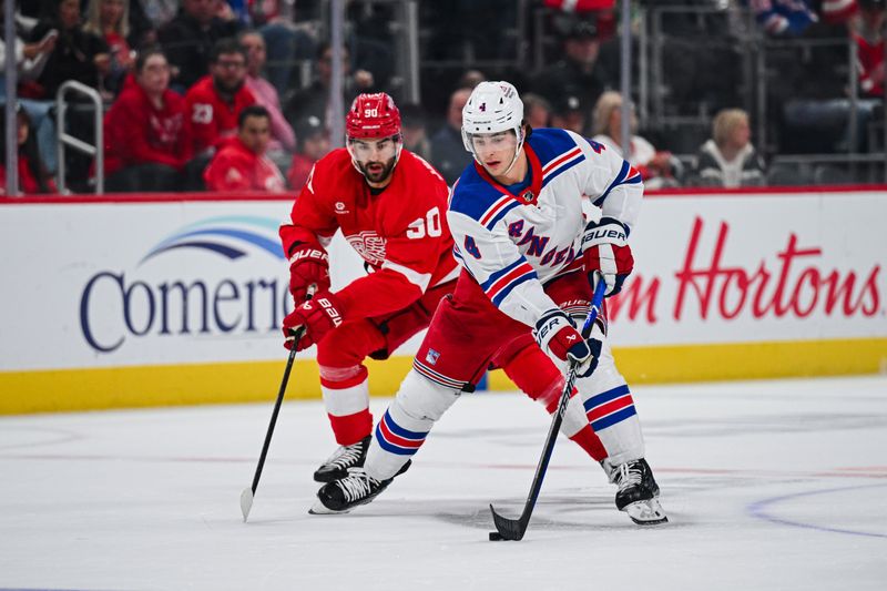 Apr 5, 2024; Detroit, Michigan, USA; New York Rangers defenseman Braden Schneider (4) brings the puck up ice against Detroit Red Wings center Joe Veleno (90) during the first period at Little Caesars Arena. Mandatory Credit: Tim Fuller-USA TODAY Sports