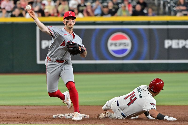 Jun 12, 2024; Phoenix, Arizona, USA; Los Angeles Angels shortstop Zach Neto (9) turns a double play on Arizona Diamondbacks catcher Gabriel Moreno (14) in the third inning at Chase Field. Mandatory Credit: Matt Kartozian-USA TODAY Sports