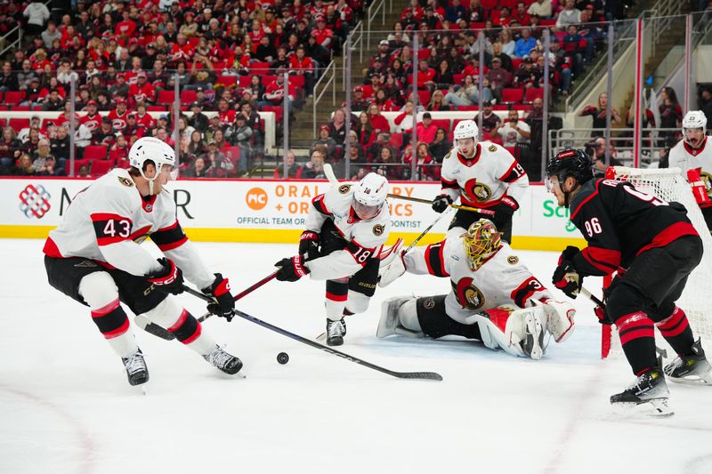 Nov 16, 2024; Raleigh, North Carolina, USA;  Ottawa Senators center Tim Stützle (18) goes to clear the puck away from goaltender Anton Forsberg (31) defenseman Tyler Kleven (43) and Carolina Hurricanes center Jack Roslovic (96) during the third period at Lenovo Center. Mandatory Credit: James Guillory-Imagn Images