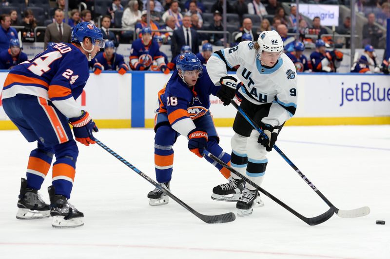 Oct 10, 2024; Elmont, New York, USA; Utah Hockey Club center Logan Cooley (92) fights for the puck against New York Islanders defensemen Alexander Romanov (28) and Scott Mayfield (24) during the first period at UBS Arena. Mandatory Credit: Brad Penner-Imagn Images