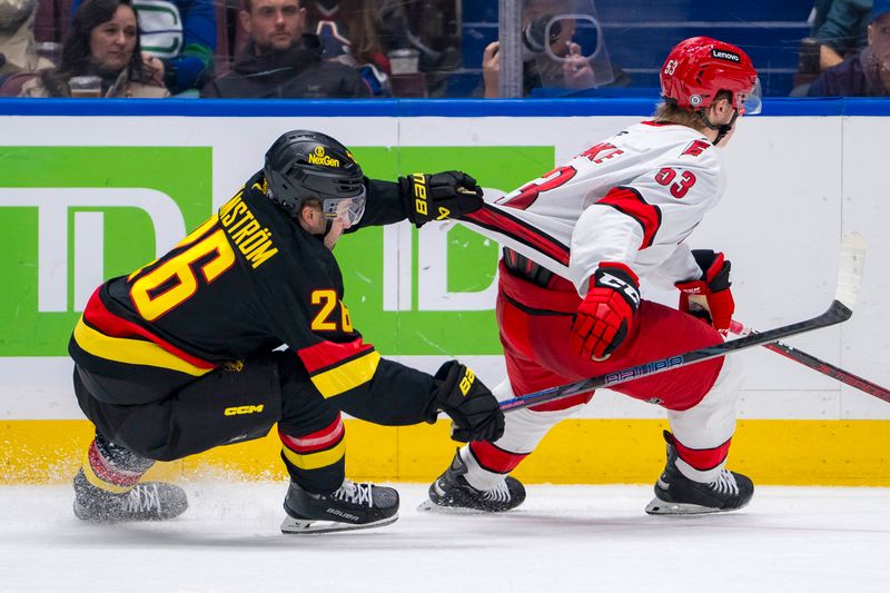 Oct 28, 2024; Vancouver, British Columbia, CAN; Vancouver Canucks defenseman Erik Brannstrom (26) grabs the shirt of Carolina Hurricanes forward Jackson Blake (53) during the second period at Rogers Arena. Mandatory Credit: Bob Frid-Imagn Images