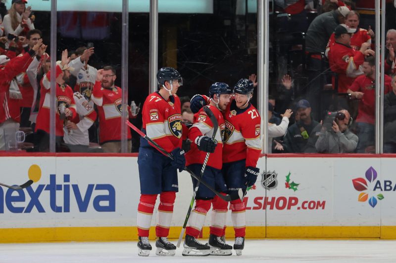 Nov 30, 2024; Sunrise, Florida, USA; Florida Panthers center Sam Bennett (9) celebrates with defenseman Niko Mikkola (77) and center Eetu Luostarinen (27) after scoring against the Carolina Hurricanes during the third period at Amerant Bank Arena. Mandatory Credit: Sam Navarro-Imagn Images