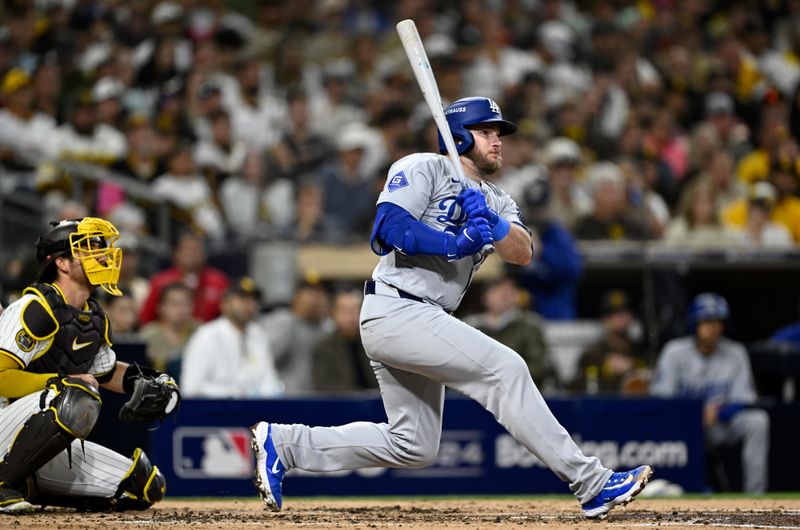 Oct 9, 2024; San Diego, California, USA; Los Angeles Dodgers third baseman Max Muncy (13) hits a double in the third inning against the San Diego Padres during game four of the NLDS for the 2024 MLB Playoffs at Petco Park.  Mandatory Credit: Denis Poroy-Imagn Images