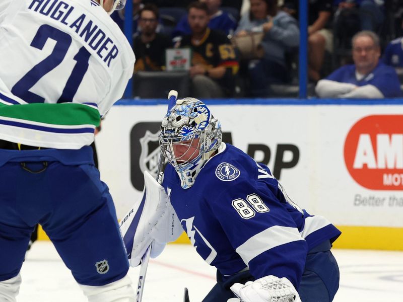 Oct 15, 2024; Tampa, Florida, USA; Tampa Bay Lightning goaltender Andrei Vasilevskiy (88) makes a save from Vancouver Canucks left wing Nils Hoglander (21) during the second period at Amalie Arena. Mandatory Credit: Kim Klement Neitzel-Imagn Images