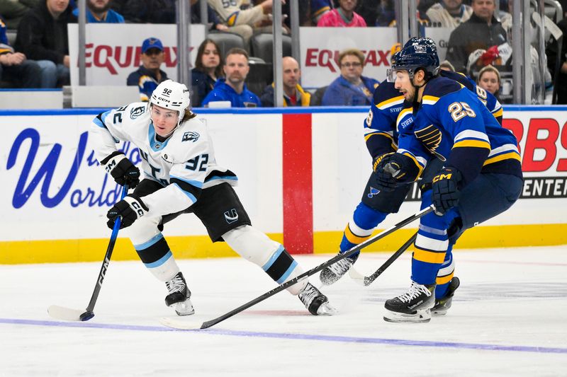 Nov 29, 2025; St. Louis, Missouri, USA; Utah Mammoth center Logan Cooley (92) controls the puck against St. Louis Blues right wing Jordan Kyrou (25) during the first period at Enterprise Center. Mandatory Credit: Jeff Curry-Imagn Images