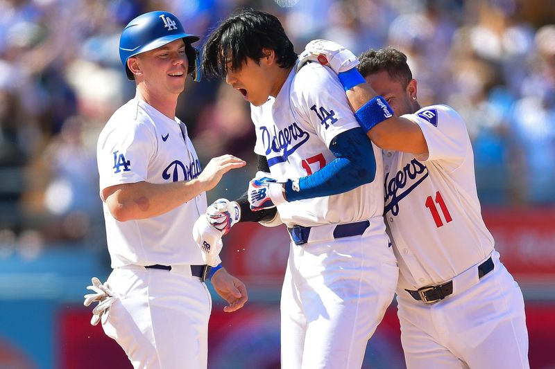 May 19, 2024; Los Angeles, California, USA; Los Angeles Dodgers shortstop Miguel Rojas (11) and catcher Will Smith (16) celebrate after designated hitter Shohei Ohtani (17) hits a walk off RBI single during the tenth inning against the Cincinnati Reds at Dodger Stadium. Mandatory Credit: Gary A. Vasquez-USA TODAY Sports