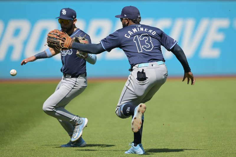 Sep 15, 2024; Cleveland, Ohio, USA; Tampa Bay Rays left fielder Dylan Carlson (10) and third baseman Junior Caminero (13) chase down a bloop double hit by Cleveland Guardians designated hitter Jose Ramirez (not pictured) during the first inning at Progressive Field. Mandatory Credit: Ken Blaze-Imagn Images