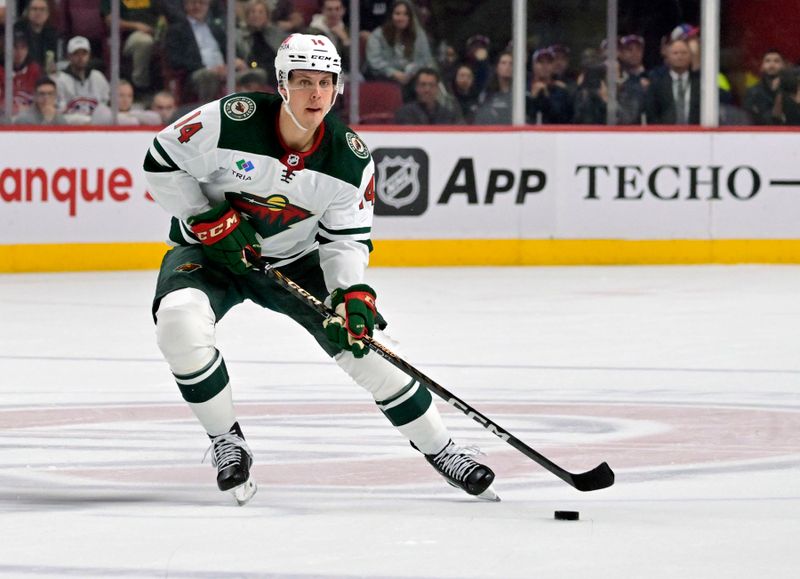 Oct 25, 2022; Montreal, Quebec, CAN; Minnesota Wild forward Joel Eriksson Ek (14) plays the puck during the first period of the game against the Montreal Canadiens at the Bell Centre. Mandatory Credit: Eric Bolte-USA TODAY Sports