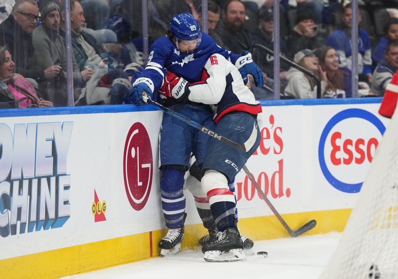 Dec 6, 2024; Toronto, Ontario, CAN; Toronto Maple Leafs left wing Nicholas Robertson (89) battles along the boards with Washington Capitals defenseman Jakob Chychrun (6) during the first period at Scotiabank Arena. Mandatory Credit: Nick Turchiaro-Imagn Images