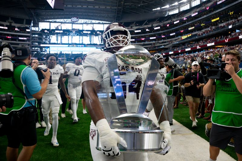 Sep 30, 2023; Arlington, Texas, USA; Texas A&M Aggies linebacker Danny Lockhart Jr. (54) carries the Southwest Classic trophy off the field after the Aggies victory over the Arkansas Razorbacks at AT&T Stadium. Mandatory Credit: Jerome Miron-USA TODAY Sports