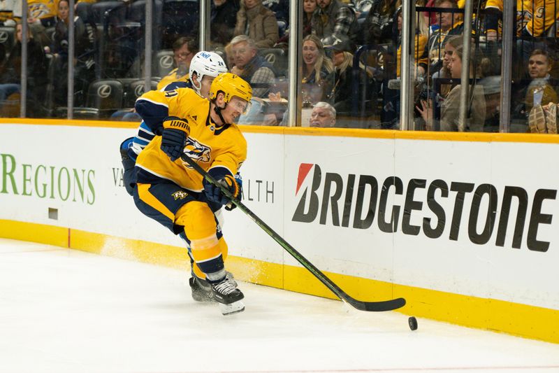 Nov 23, 2024; Nashville, Tennessee, USA;  Nashville Predators center Gustav Nyquist (14) and Winnipeg Jets defenseman Haydn Fleury (24) fight for the puck during the third period at Bridgestone Arena. Mandatory Credit: Steve Roberts-Imagn Images