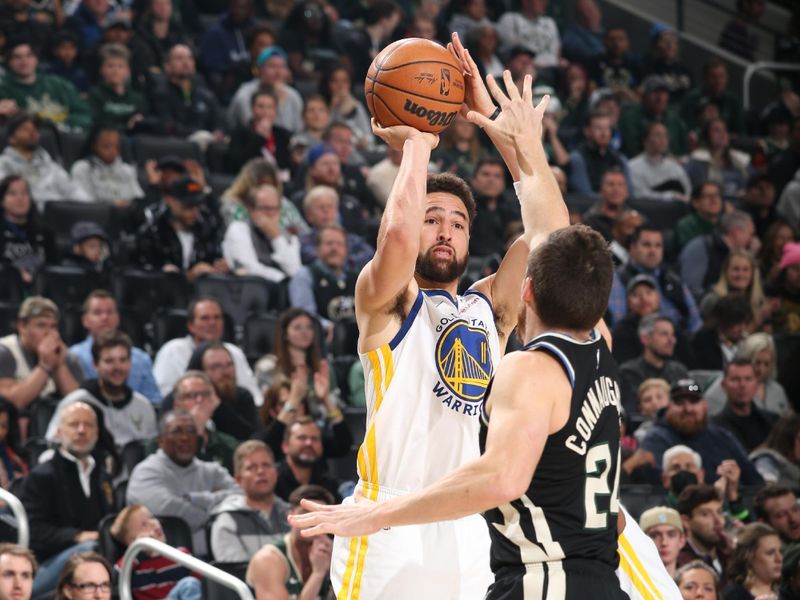 MILWAUKEE, WI - DECEMBER 13: Klay Thompson #11 of the Golden State Warriors shoots a three point basket over defender Pat Connaughton #24 of the Milwaukee Bucks during the game on December 13, 2022 at the Fiserv Forum Center in Milwaukee, Wisconsin. NOTE TO USER: User expressly acknowledges and agrees that, by downloading and or using this Photograph, user is consenting to the terms and conditions of the Getty Images License Agreement. Mandatory Copyright Notice: Copyright 2022 NBAE (Photo by Gary Dineen/NBAE via Getty Images).