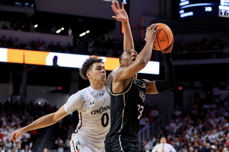 Feb 4, 2023; Cincinnati, Ohio, USA;  UCF Knights guard C.J. Kelly (13) drives to the basket against Cincinnati Bearcats guard Dan Skillings Jr. (0) in the second half at Fifth Third Arena. Mandatory Credit: Aaron Doster-USA TODAY Sports