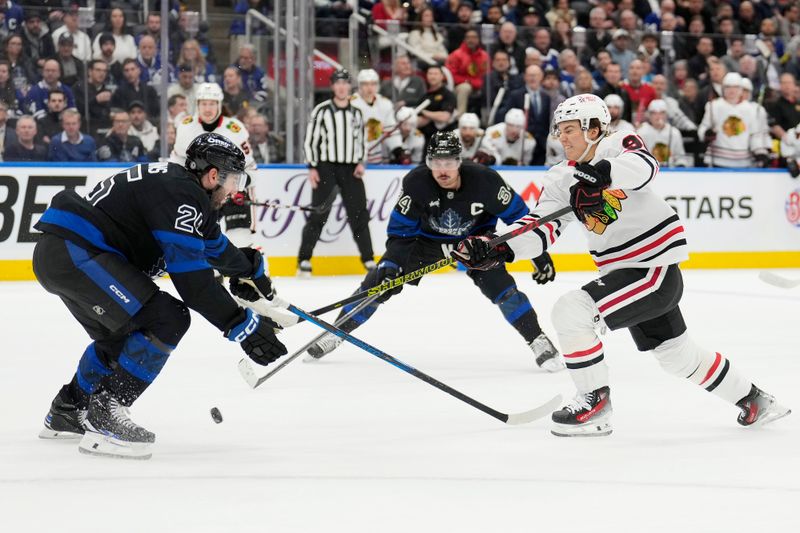 Dec 2, 2024; Toronto, Ontario, CAN; Toronto Maple Leafs defenseman Conor Timmins (25) blocks a shot from Chicago Blackhawks forward Connor Bedard (98) as Toronto Maple Leafs forward Auston Matthews (34) closes in during the second period at Scotiabank Arena. Mandatory Credit: John E. Sokolowski-Imagn Images