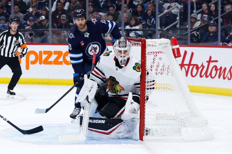 Oct 11, 2024; Winnipeg, Manitoba, CAN; Winnipeg Jets forward Gabriel Vilardi (13) and Chicago Blackhawks goalie Arvid Soderblom (40) look for the puck during the second period at Canada Life Centre. Mandatory Credit: Terrence Lee-Imagn Images