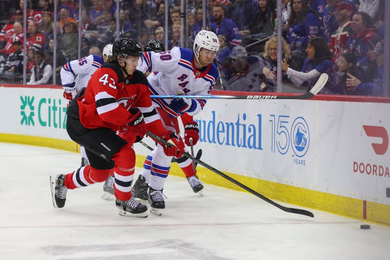 Apr 5, 2025; Newark, New Jersey, USA; New Jersey Devils defenseman Luke Hughes (43) plays the puck as New York Rangers left wing Will Cuylle (50) defends during the first period at Prudential Center. Mandatory Credit: Ed Mulholland-Imagn Images