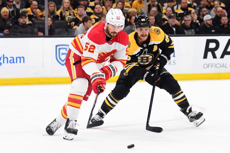 Nov 7, 2024; Boston, Massachusetts, USA;  Calgary Flames defenseman MacKenzie Weegar (52) controls the puck against Boston Bruins right wing David Pastrnak (88) during the first period at TD Garden. Mandatory Credit: Bob DeChiara-Imagn Images