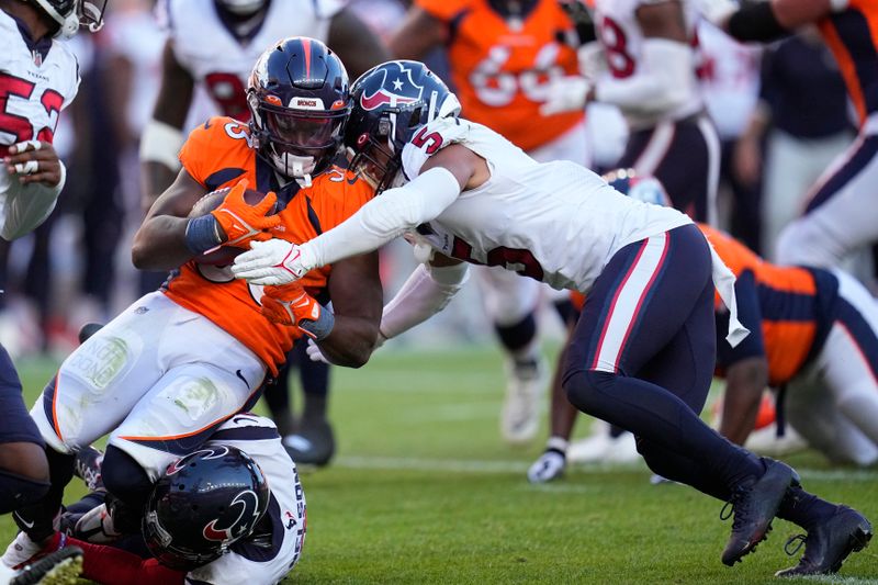 Denver Broncos running back Javonte Williams (33) is tackled by Houston Texans safety Jalen Pitre (5) during an NFL football game Sunday, Sept. 18, 2022, in Denver. (AP Photo/Jack Dempsey)