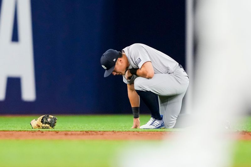 Jun 29, 2024; Toronto, Ontario, CAN; New York Yankees shortstop Anthony Volpe (11) kneels to the field during the first inning against the Toronto Blue Jays at Rogers Centre. Mandatory Credit: Kevin Sousa-USA TODAY Sports