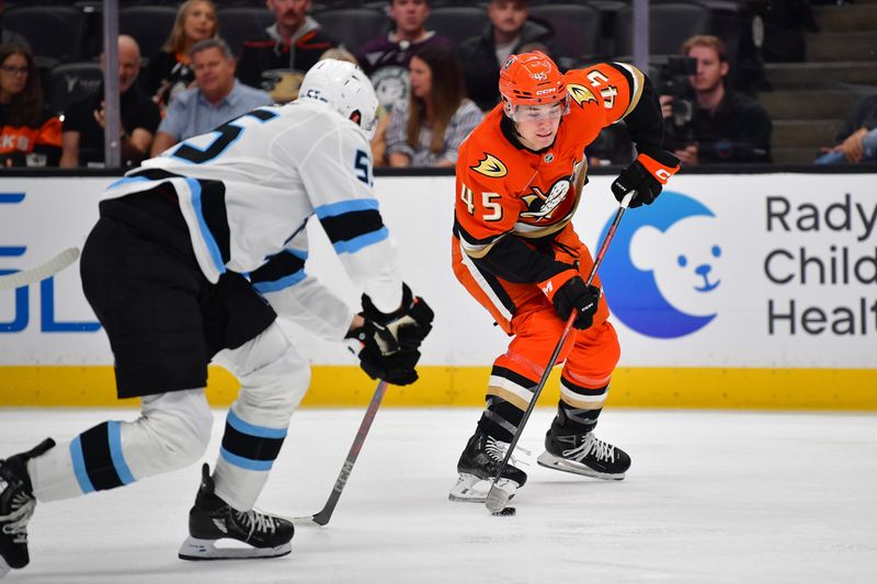 Sep 22, 2025; Anaheim, California, USA; Anaheim Ducks right wing Beckett Sennecke (45) moves the puck against Utah Mammoth defenseman Maksymilian Szuber (55) during the second period at Honda Center. Mandatory Credit: Gary A. Vasquez-Imagn Images