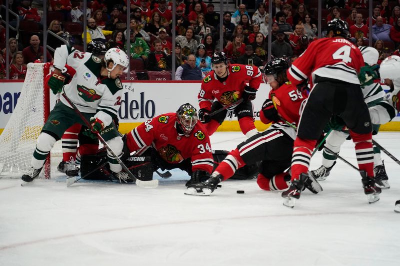 Oct 4, 2024; Chicago, Illinois, USA; Chicago Blackhawks goaltender Petr Mrazek (34) makes a save on Minnesota Wild center Marat Khusnutdinov (22) during the second period at United Center. Mandatory Credit: David Banks-Imagn Images