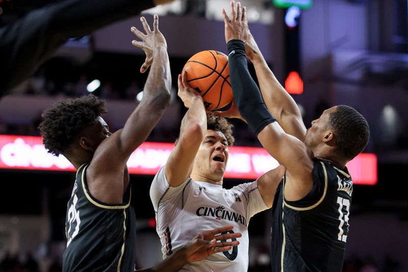 Feb 4, 2023; Cincinnati, Ohio, USA;  Cincinnati Bearcats guard Rob Phinisee (middle) drives to the basket against UCF Knights forward Taylor Hendricks (left) and guard C.J. Kelly (right) in the first half at Fifth Third Arena. Mandatory Credit: Aaron Doster-USA TODAY Sports