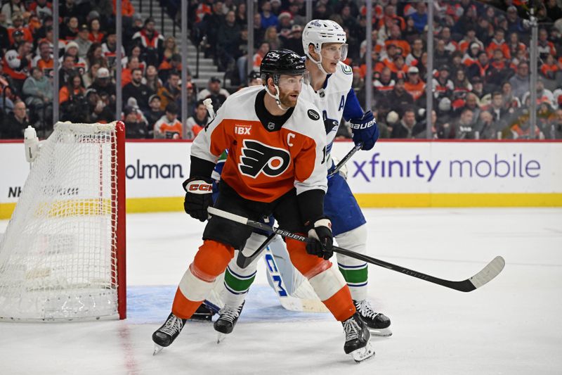 Dec 22, 2025; Philadelphia, Pennsylvania, USA; Philadelphia Flyers center Sean Couturier (14) and Vancouver Canucks defenseman Tyler Myers (57) battle for position during the second period at Xfinity Mobile Arena. Mandatory Credit: Eric Hartline-Imagn Images