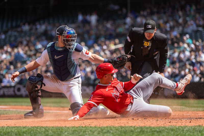 Apr 30, 2025; Seattle, Washington, USA;  Seattle Mariners catcher Mitch Garver (18) tags out Los Angeles Angels catcher Logan O'Hoppe (14) at home plate during the third inning at T-Mobile Park. Mandatory Credit: Stephen Brashear-Imagn Images