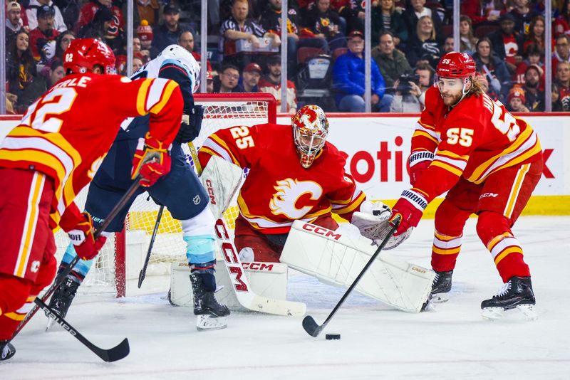 Mar 4, 2024; Calgary, Alberta, CAN; Calgary Flames defenseman Noah Hanifin (55) controls the puck in front of Calgary Flames goaltender Jacob Markstrom (25) during the third period against the Seattle Kraken at Scotiabank Saddledome. Mandatory Credit: Sergei Belski-USA TODAY Sports