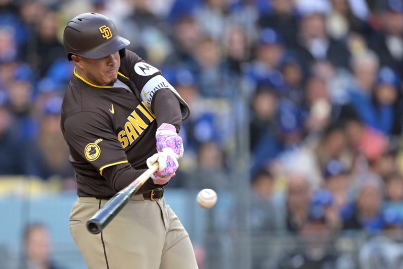 Apr 14, 2024; Los Angeles, California, USA; San Diego Padres third base Manny Machado (13) hits a solo home run in the fourth inning against the Los Angeles Dodgers at Dodger Stadium. Mandatory Credit: Jayne Kamin-Oncea-USA TODAY Sports