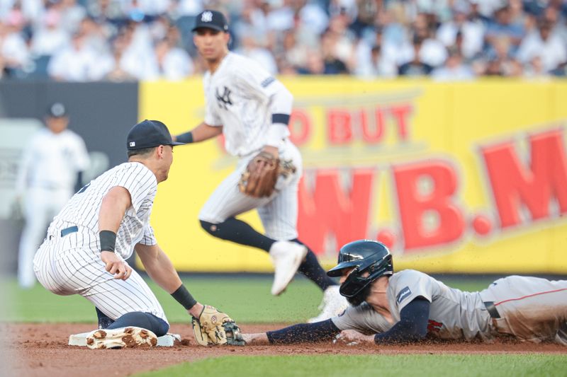 Jul 7, 2024; Bronx, New York, USA; New York Yankees shortstop Anthony Volpe (11) tags out Boston Red Sox catcher Connor Wong (12) while stealing during the second inning at Yankee Stadium. Mandatory Credit: Vincent Carchietta-USA TODAY Sports