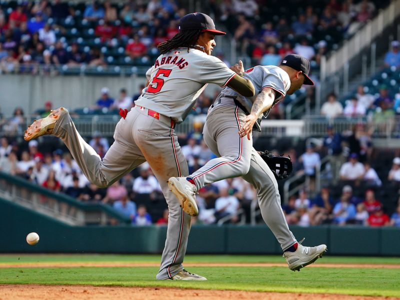 May 27, 2024; Cumberland, Georgia, USA; Atlanta Braves catcher Sean Murphy (12) hits an infield single on an error as Washington Nationals shortstop CJ Abrams (5) and Washington Nationals third baseman Nick Senzel (13) bobble the ball during the ninth inning at Truist Park. Mandatory Credit: John David Mercer-USA TODAY Sports