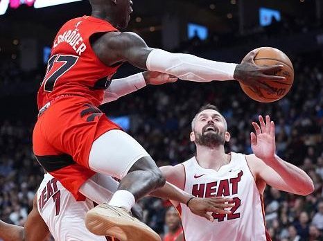 TORONTO, ON - DECEMBER 6: Dennis Schroder #17 of the Toronto Raptors passes the ball off against Kevin Love #42 of the Miami Heat during the second half of their basketball game at the Scotiabank Arena on December 6, 2023 in Toronto, Ontario, Canada. NOTE TO USER: User expressly acknowledges and agrees that, by downloading and/or using this Photograph, user is consenting to the terms and conditions of the Getty Images License Agreement. (Photo by Mark Blinch/Getty Images)