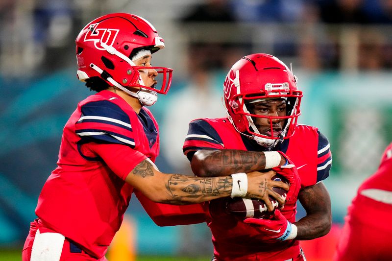 Dec 20, 2022; Boca Raton, Florida, USA; Liberty Flames quarterback Kaidon Salter (7) hands the ball to running back Shedro Louis (1) during the second quarter in the 2022 Boca Raton Bowl at FAU Stadium. Mandatory Credit: Rich Storry-USA TODAY Sports