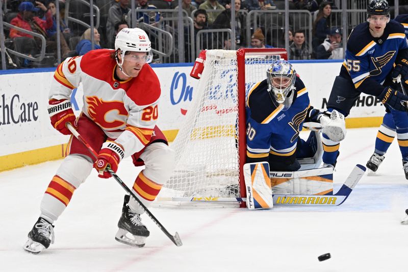 Jan 16, 2025; St. Louis, Missouri, USA; St. Louis Blues goaltender Joel Hofer (30) defends the net as Calgary Flames center Blake Coleman (20) makes a pass in the first period at Enterprise Center. Mandatory Credit: Joe Puetz-Imagn Images