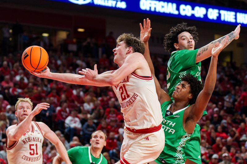 Dec 21, 2025; Lincoln, Nebraska, USA; Nebraska Cornhuskers forward Pryce Sandfort (21) shoots the ball against North Dakota Fighting Hawks forward Marley Curtis (0) and center Josh Jones (22) during the first half at Pinnacle Bank Arena. Mandatory Credit: Dylan Widger-Imagn Images