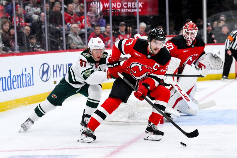 Oct 22, 2025; Newark, New Jersey, USA; New Jersey Devils center Nico Hischier (13) skates with the puck while defended by Minnesota Wild left wing Kirill Kaprizov (97) during the first period at Prudential Center. Mandatory Credit: John Jones-Imagn Images