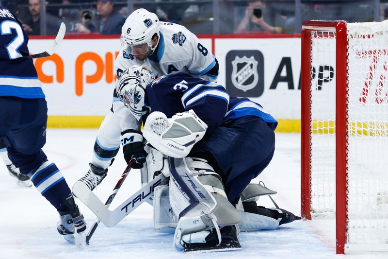 Nov 5, 2024; Winnipeg, Manitoba, CAN;  Winnipeg Jets goalie Connor Hellebuyck (37) and Utah Hockey Club forward Nick Schmaltz (8) look for the puck during the first period at Canada Life Centre. Mandatory Credit: Terrence Lee-Imagn Images