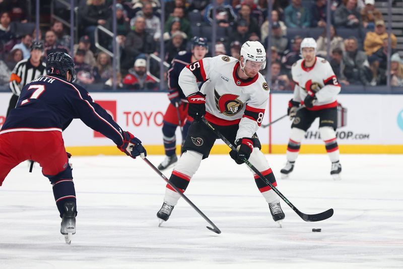 Dec 11, 2025; Columbus, Ohio, USA; Ottawa Senators defenseman Jake Sanderson (85) controls the puck as Columbus Blue Jackets defenseman Brendan Smith (7) defends during the first period at Nationwide Arena. Mandatory Credit: Joseph Maiorana-Imagn Images