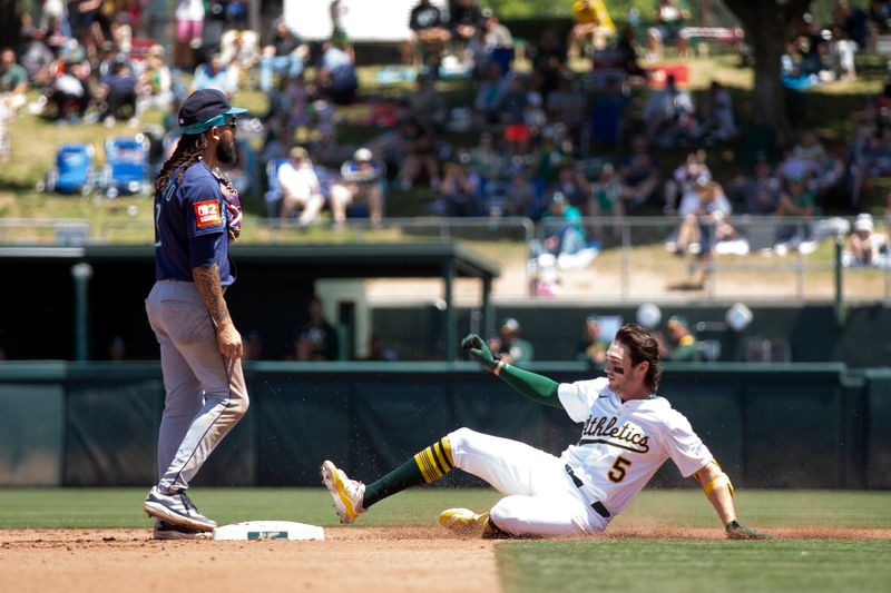 May 7, 2025; West Sacramento, California, USA; Athletics shortstop Jacob Wilson (5) slides safely into second base with his second double of the game against the Seattle Mariners, during the fourth inning at Sutter Health Park. Shortstop J.P. Crawford (3) is at left. Mandatory Credit: D. Ross Cameron-Imagn Images
