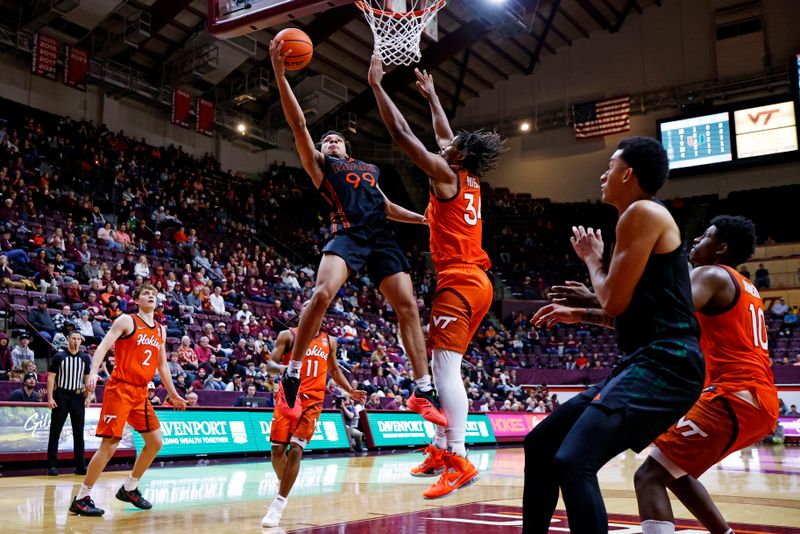 Jan 4, 2025; Blacksburg, Virginia, USA; Miami Hurricanes guard Divine Ugochukwu (99) shoots the ball against Virginia Tech Hokies forward Mylyjael Poteat (34) during the second half at Cassell Coliseum. Mandatory Credit: Peter Casey-Imagn Images