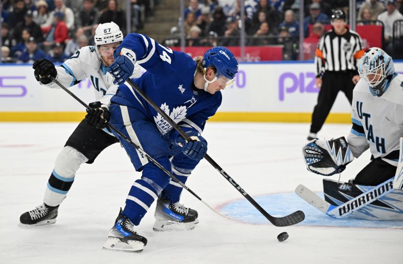 Nov 24, 2024; Toronto, Ontario, CAN;  Toronto Maple Leafs forward Bobby McMann (74) plays the puck against Utah Hockey Club forward Barrett Hayton (27) and goalie Karel Vejmelka (70) in the third period at Scotiabank Arena. Mandatory Credit: Dan Hamilton-Imagn Images