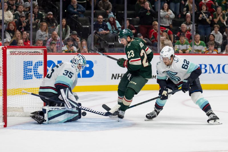 Oct 12, 2024; Saint Paul, Minnesota, USA; Minnesota Wild center Marco Rossi (23) has the puck checked away by Seattle Kraken goaltender Joey Daccord (35) while defenseman Brandon Montour (62) checks him from behind in the overtime period at Xcel Energy Center. Mandatory Credit: Matt Blewett-Imagn Images